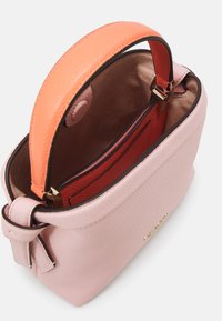 Borsa strutturata in pelle rosa con manico arancione. Interno con fodera in tessuto rosso e tasca con zip, dal design minimalista.