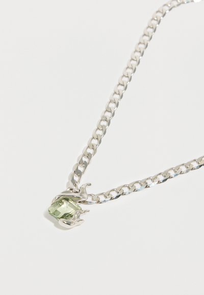 Sudraba ķēdes kaklarota ar taisnstūrveida zaļu dārgakmeni, kuru ieskauj vērpti metāla akcenti. Gluda tekstūra ar pulētu virsmu.