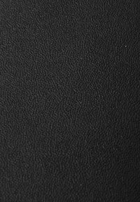 Materiale in tessuto nero con una trama sottile, caratterizzato da una superficie fine e leggermente in rilievo. Adatto a diverse applicazioni, offre durata e stile.