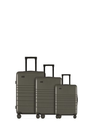Set of three hard-shell suitcases in dark green, featuring textured lines, telescopic handles, and four wheels for mobility.