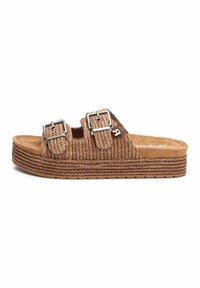 Sándala tejida marrón tipo slip-on con dos hebillas ajustables, parte superior texturizada y una suela intermedia de yute en capas, con una suela de goma plana.