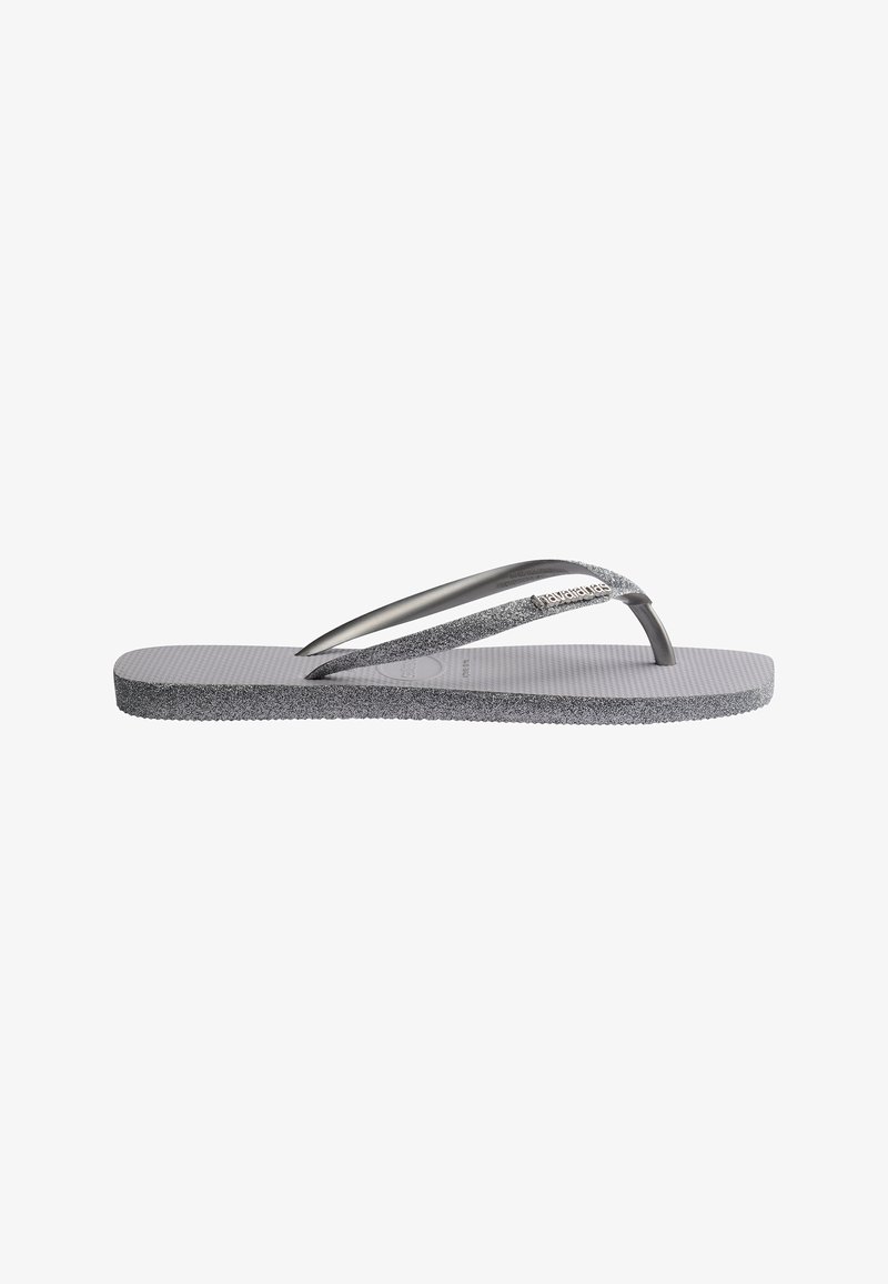 Tongs grises avec semelle texturée et brides grises scintillantes, comportant un petit logo de marque sur la bride supérieure.