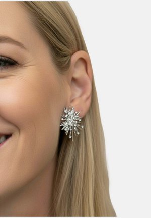 Ezüst csillagrobbanás fülbevalók hosszúkás, kúpos tüskékkel, apró kristály díszítéssel, melyek visszaverik a fényt és kiemelik a dizájnt.