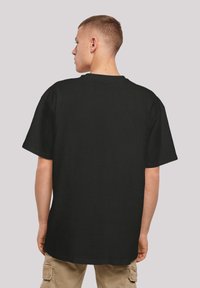 Black cotton t-shirt with short sleeves and a round neck, featuring a relaxed fit and flat hem, shown from the back with no visible patterns.