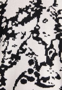 Knit fabric featuring a black and white abstract pattern with varying shapes and textures, emphasizing contrast and intricate details.