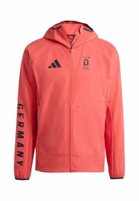 Koraalrode jas met ritssluiting en capuchon, voorzien van zwarte accenten, "TEAM D"-logo, Olympische ringen en tekst "GERMANY" op de mouw. Gladde textuur.