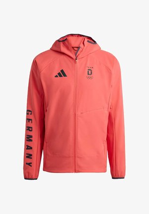 Korallfärgad zipjacka med huva, med svarta detaljer, "TEAM D"-logotyp, olympiska ringar och texten "GERMANY" på ärmen. Mjuk textur.