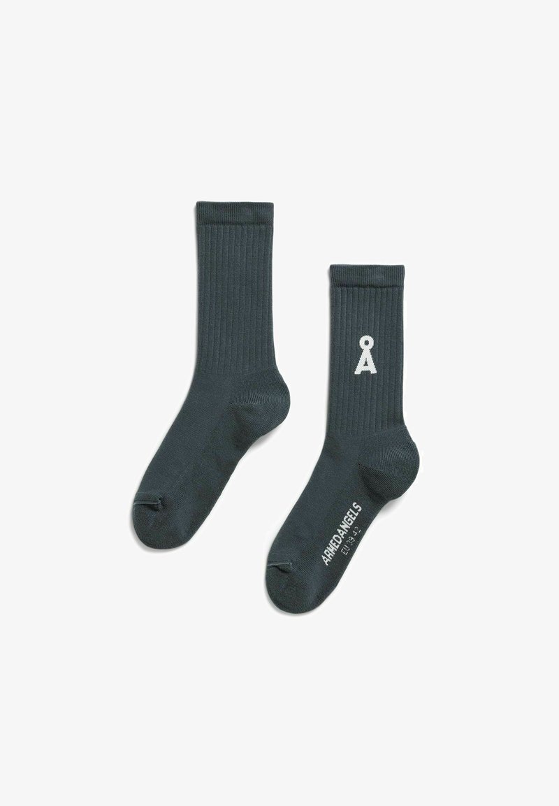 Dunkelgrüne, gerippte Socken mit weißem Logo und Markennamen auf der Sohle, hergestellt aus einem weichen, dehnbaren Material.