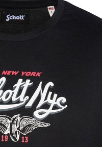 Camiseta de algodón negra con cuello redondo y gráfico impreso con "Schott NY" en blanco y rojo, además de un detalle de diseño alado.