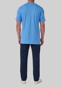 Hemelsblauw T-shirt met korte mouwen en een klassieke snit, gecombineerd met marineblauwe broek. De achterkant van het shirt is glad en de broek heeft een relaxte pasvorm.