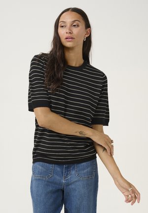 Black short-sleeve sweater with horizontal white stripes. Ribbed neckline and cuffs. Smooth texture, relaxed fit, worn with blue jeans.