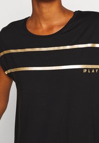 Camiseta negra de manga corta, con Rayas horizontales doradas y el logo "Only Play" en dorado. Textura de algodón suave, corte relajado.