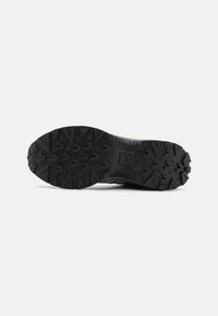 Black rubber outsole with a rugged tread pattern. Reinforced edges and grooves enhance traction and durability. Suitable for outdoor use.