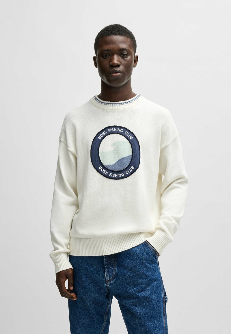 Felpa bianca a maglia con un logo ricamato rotondo "BOSS FISHING CLUB" che presenta onde blu. Polsini e orlo a coste, vestibilità rilassata.