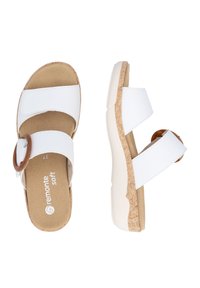 White slide sandals featuring two wide straps, a round brown buckle, and a textured beige sole with a cork design.