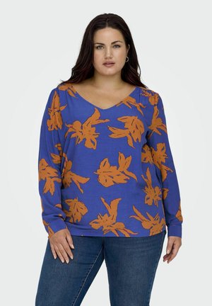 Langemouwen top in felblauw met een oranje bloemenpatroon, voorzien van een V-hals en zachte, gestructureerde stof. Gestyled met jeans.