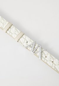 Ceinture blanche texturée avec un motif géométrique, dotée d'une boucle métallique argentée avec des lettres "A" stylisées, ajustable avec des boucles en cuir.