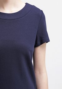 Haut bleu marine à manches courtes avec une texture lisse et un col rond. Présente un motif à côtes sur l'ensemble du tissu.