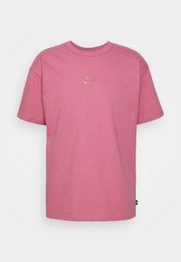 Rosa bomullströja med korta ärmar, rund hals och liten broderad Nike-logotyp på bröstet. Slät textur, avslappnad passform.