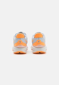 Baskets de sport grises avec des accents orange. Elles possèdent une tige en mesh, une semelle rembourrée et une semelle extérieure en caoutchouc texturé. Logo en étoile au talon.