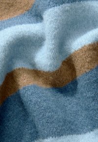 Tissu tricoté présentant des rayures alternées de bleu clair, bleu foncé et beige. Texture douce avec une apparence légèrement duveteuse.