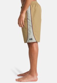 Μπεζ μαγιό σορτς με πλευρικά πάνελ καρό, ελαστική μέση και μαύρη ετικέτα. Διαθέτει αντίθετη ραφή και κανονικό μήκος.