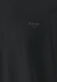 Fekete, rövid ujjú póló, puha pamutból készült, amelyen diszkrét bélyegzett "JOOP! JEANS" logó található egy sötétebb árnyalatban a mellkasán.