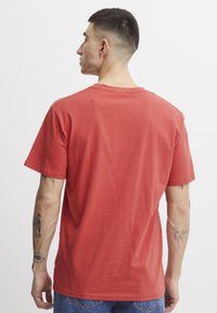 Rød bomulls T-skjorte med korte ermer og rund hals, med et enkelt design. Stoffet ser ut til å være mykt med en jevn tekstur.