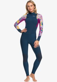 Traje de neopreno azul marino con mangas largas, detalles de estampado floral en rosa y amarillo, costuras planas y parches de refuerzo en las rodillas.