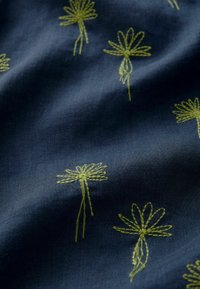 Marine stof met gele geborduurde bloemenpatronen, met unieke vormen en textuurdetails die een zachte uitstraling creëren.