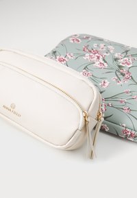 To kosmetikpunge: en cremefarvet struktureret taske med gylden lynlås og en grøn taske med blomsterprint, begge med lynlås og forskellige designs.