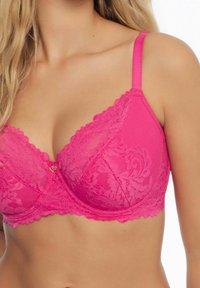Fuksjowy stanik z koronką, posiadający kwiatowy wzór, regulowane satynowe ramiączka oraz dekoracyjny akcent w kształcie serca pomiędzy miseczkami.