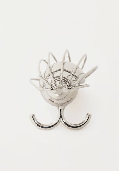 Γυαλισμένος ασημένιος γάντζος τοίχου με οκτώ καμπυλωτές ακίδες που σχηματίζουν κυκλικό μοτίβο πάνω από δύο στρογγυλεμένους γάντζους σε λευκό φόντο.
