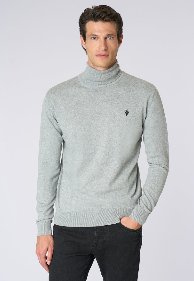 Maglione a collo alto grigio chiaro realizzato in un morbido tessuto a maglia. Presenta un design aderente, maniche lunghe e un piccolo logo ricamato sul petto.