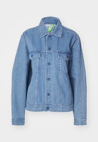 Ljusblå denimjacka med knäppning fram, två bröstfickor och sidofickor. Har en klassisk krage och subtil ribbad textur.