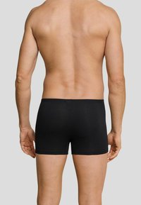 Black boxer briefs made of soft fabric, featuring a snug fit and a simple design. The waistband is elastic, ensuring comfort and support.