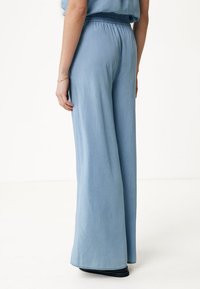 Jasnoniebieskie spodnie szerokie, wykonane z teksturowanej tkaniny, z elastycznym pasem i luźnym krojem, sięgające do podłogi.