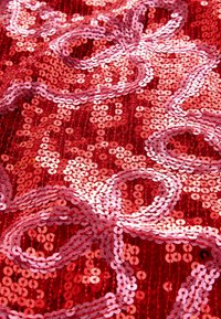 Tessuto rosso con paillettes sovrapposte a forma di cerchi, con un motivo a onde, accentuato da paillettes rosa, che creano texture e brillantezza.