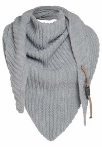 Lichtgrijze gebreide sjaal met een geribbelde structuur, driehoekige vorm en lange, hangende uiteinden. Bevat een leren accent met een label.