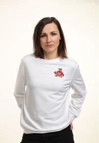 Sudadera de manga larga blanca con un gráfico de un personaje de dibujos animados colorido en el pecho. Material de algodón suave con un corte relajado.