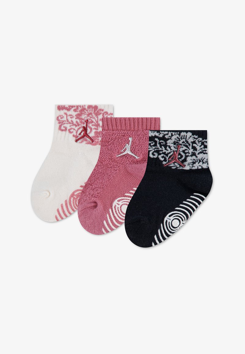 Trois chaussettes pour bébé en blanc, rose et noir, chacune avec des motifs décoratifs et un petit logo Jumpman au niveau de la cheville.