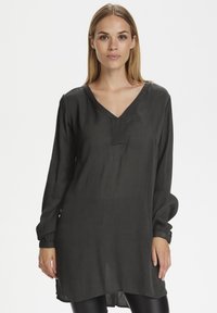 Tunic grigio scuro a maniche lunghe con scollatura a V, realizzata in tessuto leggero, caratterizzata da una superficie leggermente texture e un fit morbido.