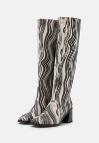Botas até ao joelho com um padrão ondulado preto e branco, bico fino, superfície texturizada e um salto robusto para maior estabilidade.