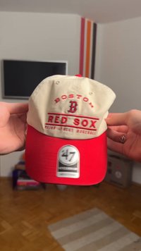 Baseballová čiapka v béžovej a červenej farbe. Na prednej strane je vystupujúci nápis "BOSTON RED SOX". Látka má hladkú textúru. Na štíte je značená nálepka.
