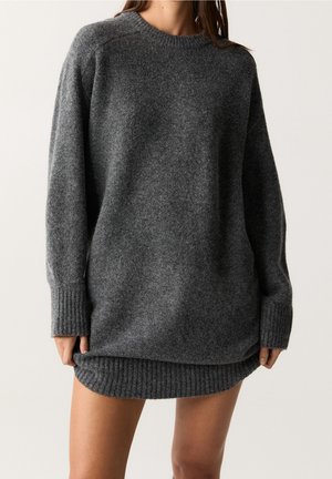 Pull en tricot gris surdimensionné avec des poignets et un ourlet côtelés, présentant une finition texturée et un col rond. Coupe décontractée, longueur hanches.