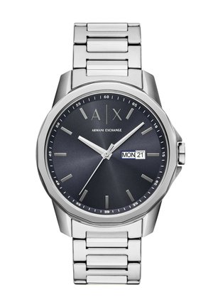 Montre en acier inoxydable avec un cadran bleu foncé, des index argentés, un affichage de la date et un bracelet en maillons métalliques brossés. Design de boîtier rond.