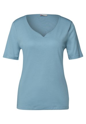 Ljusblå top med V-ringning och kort ärm, i ett mjukt tyg, avslappnad passform, rena kanter, med en subtil etikett vid halsringningen.