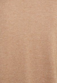 Tissu en maille côtelée marron clair, finement texturé avec une surface lisse. Répartition uniforme de la couleur, sans motifs ni ornements visibles.