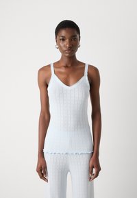 Helles blaues gestricktes Tanktop mit V-Ausschnitt, das ein strukturiertes Muster aufweist. Der Saum hat eine gewellte Kante und schmale Träger.