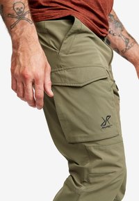 Cargo byxor i olivgrön färg, tillverkade av slitstark tyg. Har flera fickor och sömnadsdetaljer. Broderad logotyp på låret.
